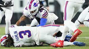 Bills football player Damar Hamlin laying on the field after he collapsed with his teammates standing over him checking on him.