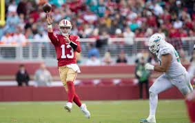 football player throwing on the run with another chasing after him.