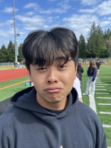 Asian American person, head shot with some body standing on turf.